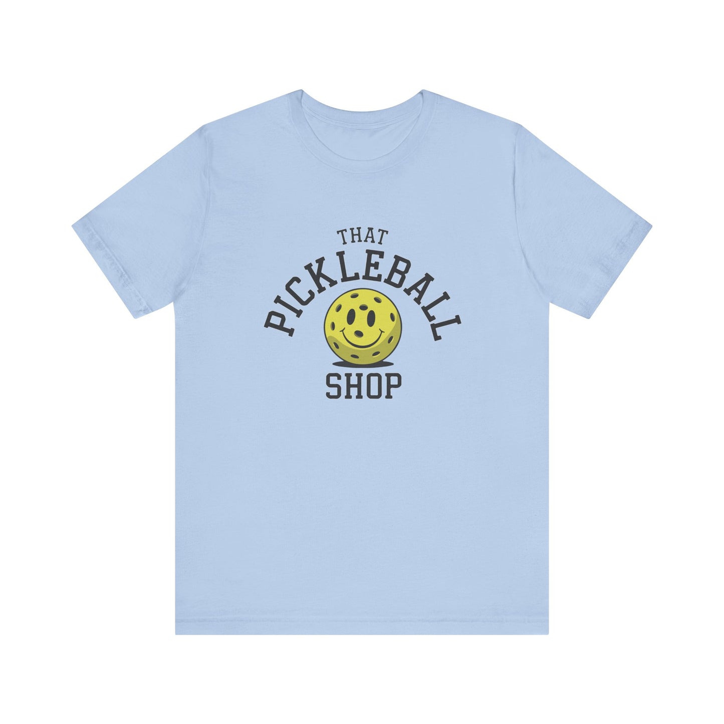 Light blue t-shirt featuring That Pickleball Shop logo with a yellow pickleball smiley face.