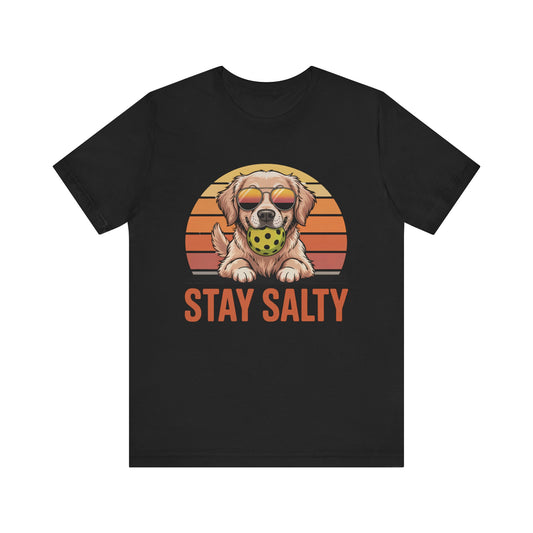 tay Salty Dog pickleball t-shirt featuring golden retriever with sunglasses and pickleball in mouth against retro sunset stripes